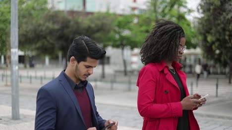Afro-american-woman-and-mixed-race-man-walking,-texting-on-phone